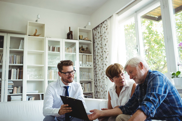 agent and elderly couple look at a laptop