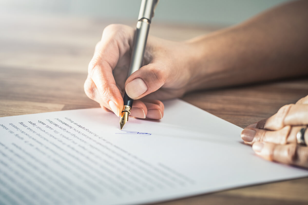 Woman signs a contract with a fountain pen
